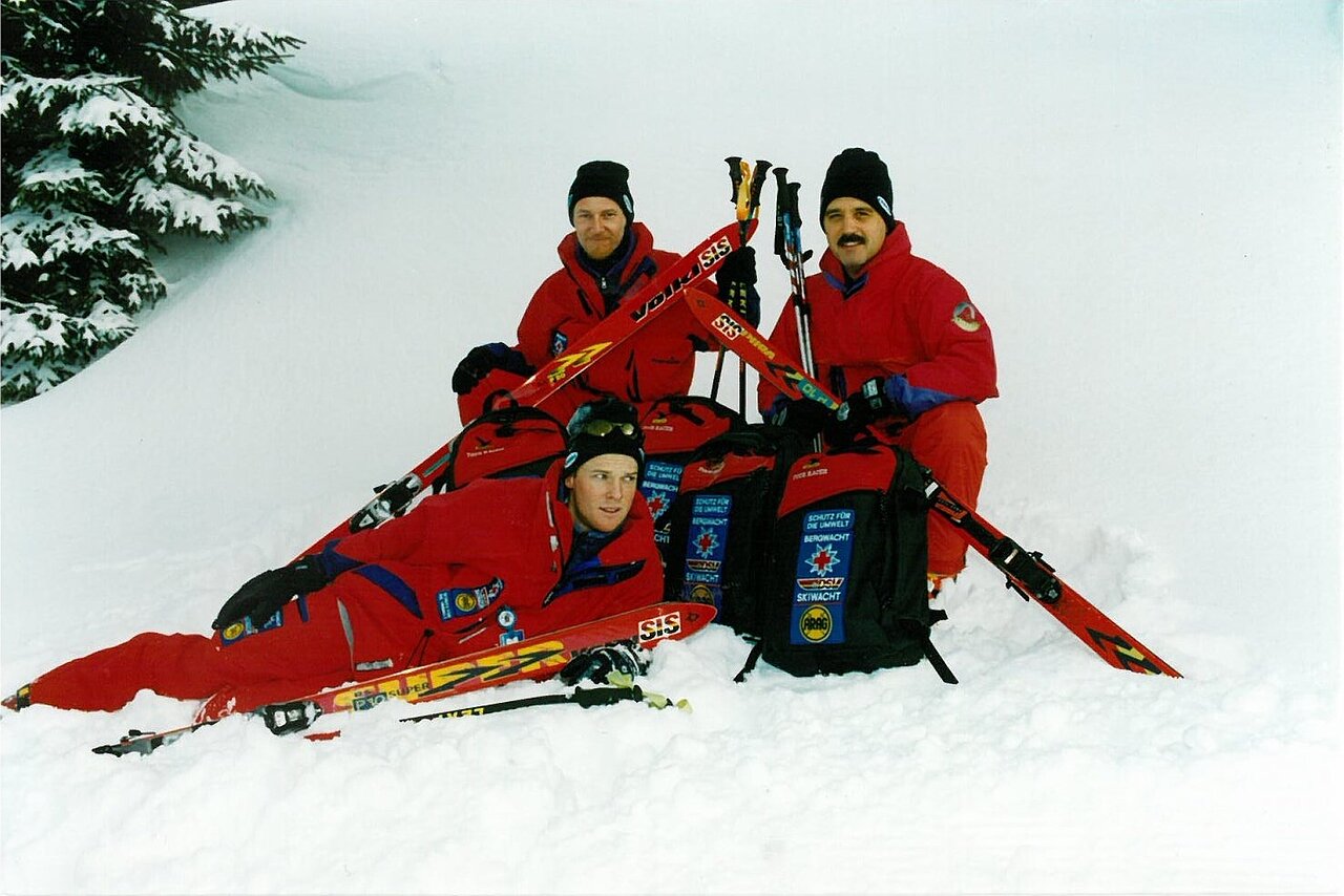 Historisches Bild der DSV Skiwacht. 3 Skiwächtler im Schnee mit Ausrüstung.