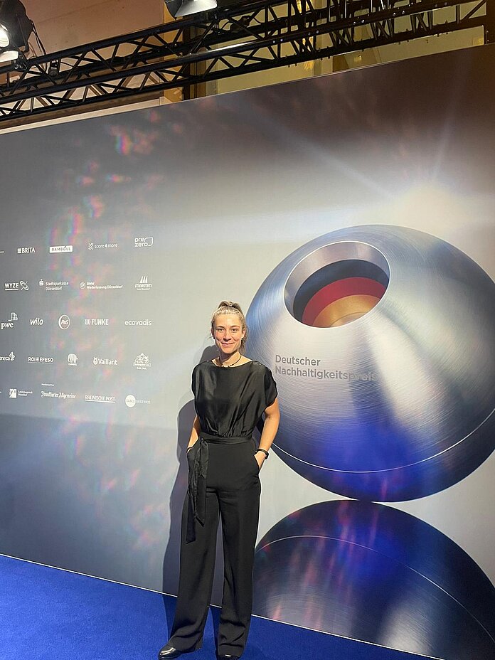 Foto einer Frau vor dem Hintergrund des Deutschen Nachhaltigkeitspreises